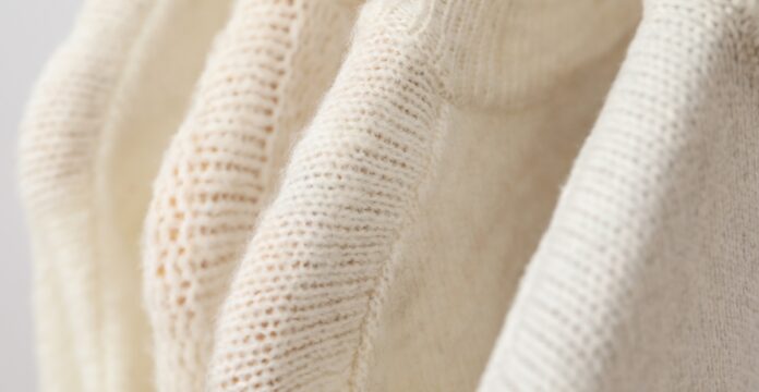 Heavyweight Recycled Cashmere Fabric A close-up of cream-colored heavyweight recycled cashmere fabric, with visible knit texture and soft folds.