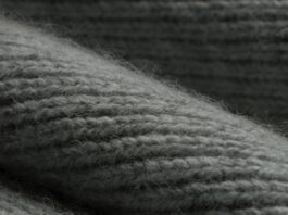 Knit Pure Cashmere Fabric Close-up of a gray knitted cashmere fabric, showing textured ridges and fibers with soft, diffuse lighting.