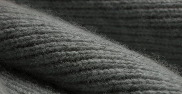 Knit Pure Cashmere Fabric Close-up of a gray knitted cashmere fabric, showing textured ridges and fibers with soft, diffuse lighting.