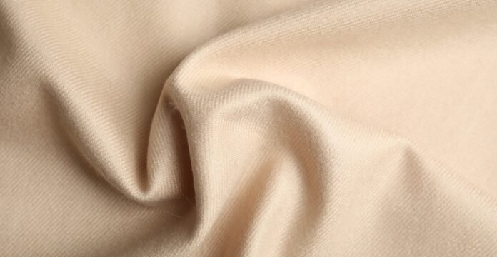 Lightweight Grade B Cashmere Fabric Close-up of beige cashmere fabric with soft folds and draped texture.