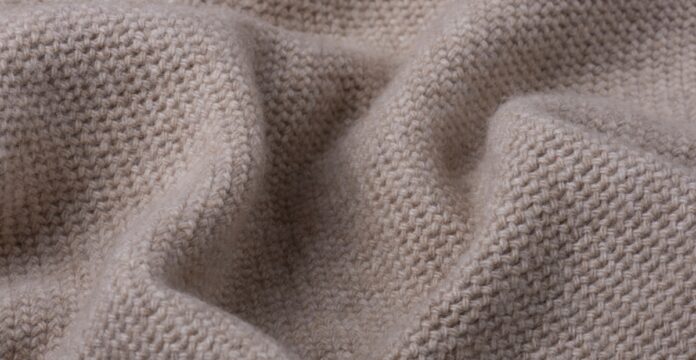 Lightweight Pure Cashmere Fabric Close-up of a lightweight, light-brown knitted cashmere fabric with a dense, uniform knit pattern and soft folds.