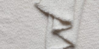 Benefits of Lightweight Recycled Cashmere Fabric Lightweight Recycled Cashmere Fabric A close-up view of a cream-colored knitted fabric with a wavy, folded edge, showing the textured knit pattern.