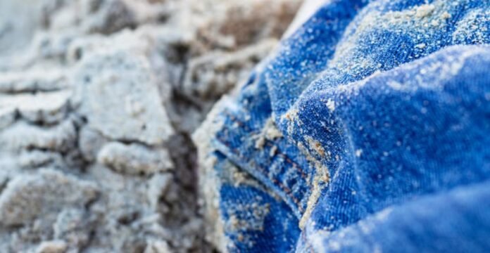 Alt text: Close-up of blue jeans with sand clinging to the fabric, draped against a blurred sandy background. Cold-Blocking Fabric: