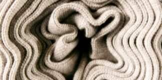 What Is Thermal Core Fabric for Winter Wear? Complete Guide Alt text: Close-up of a folded, cream-colored knit fabric with thick, wavy ridges creating a plush, textured appearance. What Is Thermal Core Fabric for Winter Wear?