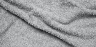 Polar Warm Weave Fabric Explained: Features, Benefits & Uses Alt text: Close-up of a gray plush towel with a soft, fluffy texture and gentle folds casting shadows. Polar Warm Weave Fabric Explained: