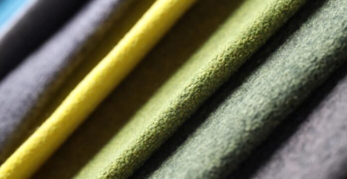 Alt text: Close-up of layered, textured fabric in muted greens with a bright yellow strip, showcasing soft, fuzzy material. Why Alpine Therm Winter Fabric?