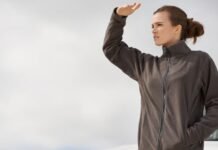 What Is Wind Armor Extreme Fabric? Features, Benefits & Uses Alt text: A woman stands outdoors wearing a dark gray zip-up winter coat, shielding her eyes with her hand as she looks into the distance. What Is Wind Armor Extreme Fabric?