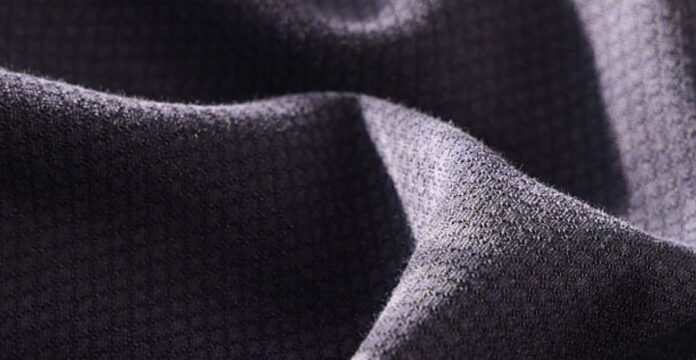 Alt text: Close-up of textured, folded fabric in dark gray with a rough surface; light highlights the peaks and shadows in the folds. What Is Thermal Core Elite Fabric?
