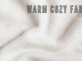Alt text: A close-up view of cream-colored fabric with soft folds and shadows, conveying a warm, cozy texture. The text "WARM COZY FABRIC" appears across the top in bold, shadowed lettering. Ever Warm Cozy Fabric Guide: