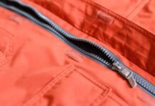 Storm Warm Insulation Fabric: Ultimate Winter Warmth Guide Close-up of an orange winter coat with a partially unzipped gray-lined zipper; visible pockets and Velcro closures along the fabric.Storm Warm Insulation Fabric: