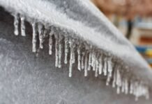 Ice Barrier Windproof Fabric: Advanced Shield Against Cold Alt text: Close-up of a gray, textured surface with many icicles hanging from its edge; a blurred background shows hints of a building and trees. Ice Barrier Windproof Fabric: