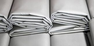 Frost Core Insulated Fabric: Ultimate Winter Warmth Solution Alt text: Close-up of neatly folded, light gray fabric bundles stacked in a row, with horizontal lines and soft shadows. Frost Core Insulated Fabric: