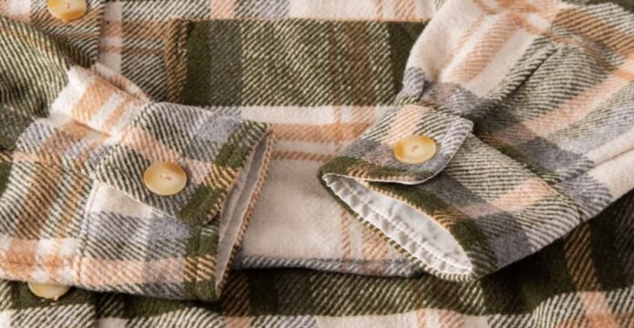 Close-up of a plaid winter shirt or coat sleeve with beige buttons, showing soft, flannel-like fabric in green, orange, cream tones. Sherpa Lined Fabric Guide: