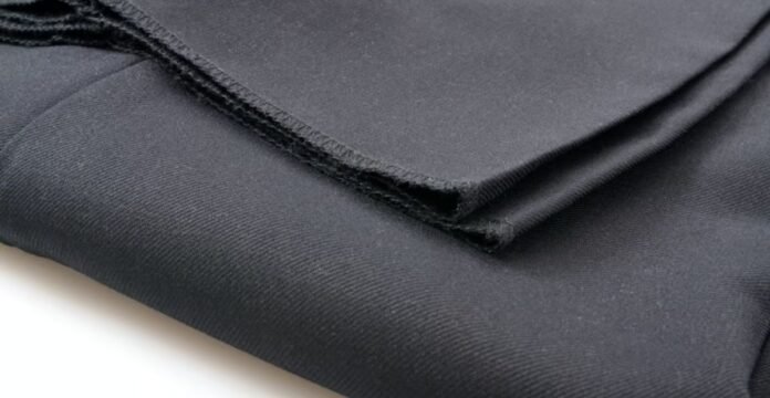 Alt text: Close-up of folded black fabric with a visible seam, resting on a white surface. Polar Guard Heat Retention Fabric: