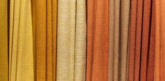 Warm Aura Fabric Explained:Why It’s Perfect for Cold Weather Alt text: Close-up of vertical fabric drapes in a gradient from light yellow to dark orange, showing a mix of smooth and textured surfaces. Warm Aura Fabric Explained: