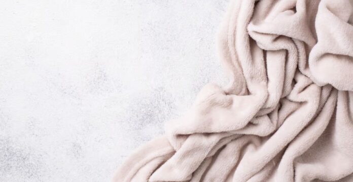 Cloud Fleece Winter Fabric: Alt text (short, descriptive): A pale pink plush blanket draped in soft folds against a light gray speckled background. Cloud Fleece Winter Fabric:Cloud Fleece Winter Fabric: