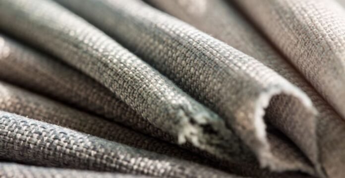 Close-up of folded woven fabric in gray and beige tones, showing a clear weave texture and soft lighting that highlights depth. Heat-Retaining Fabric Explained: