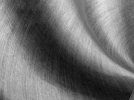 Alt text: Close-up of a draped linen fabric in grayscale, showing visible weave and soft lighting that highlights folds and curves for a textured, abstract effect. Alpine Silk Shield Fabric:
