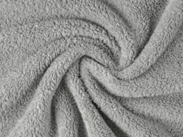 A close-up of gray fluffy fabric with a soft, dense texture arranged in a swirling pattern, creating depth and movement. Nordic Plush Thermal Fabric Explained: