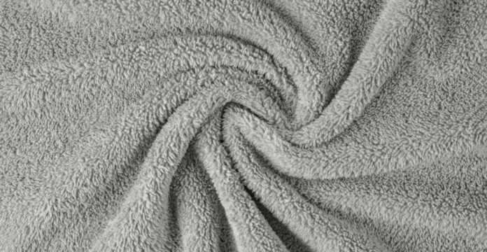 A close-up of gray fluffy fabric with a soft, dense texture arranged in a swirling pattern, creating depth and movement. Nordic Plush Thermal Fabric Explained: