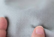 Thermo Shield Performance Fabric: Technology for Activewear Close-up of light gray textured fabric being pinched by two fingers.Thermo Shield Performance Fabric: