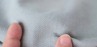 Thermo Shield Performance Fabric: Technology for Activewear Close-up of light gray textured fabric being pinched by two fingers.Thermo Shield Performance Fabric: