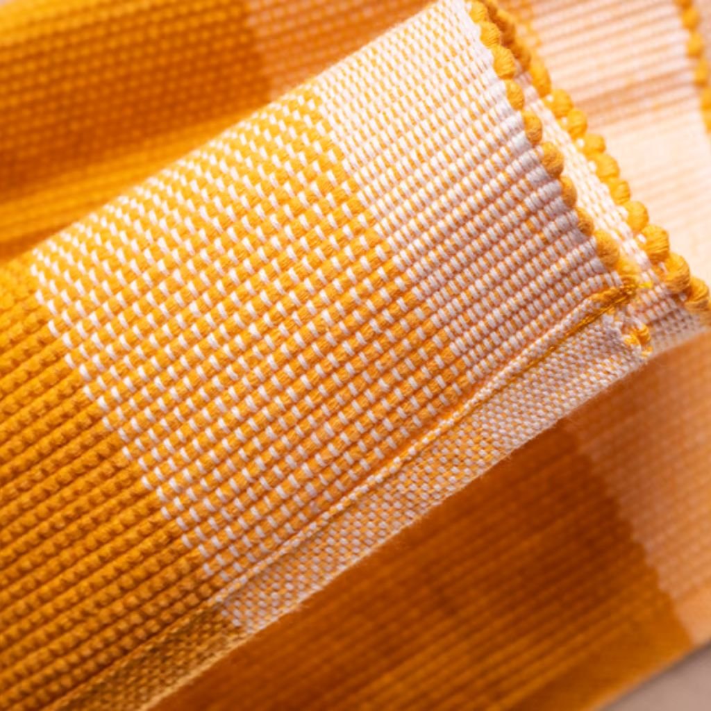 Close-up of folded yellow and white woven fabric with a checked pattern, showing a seam with small rounded edge details.

Heat-Retaining Fabric Explained: