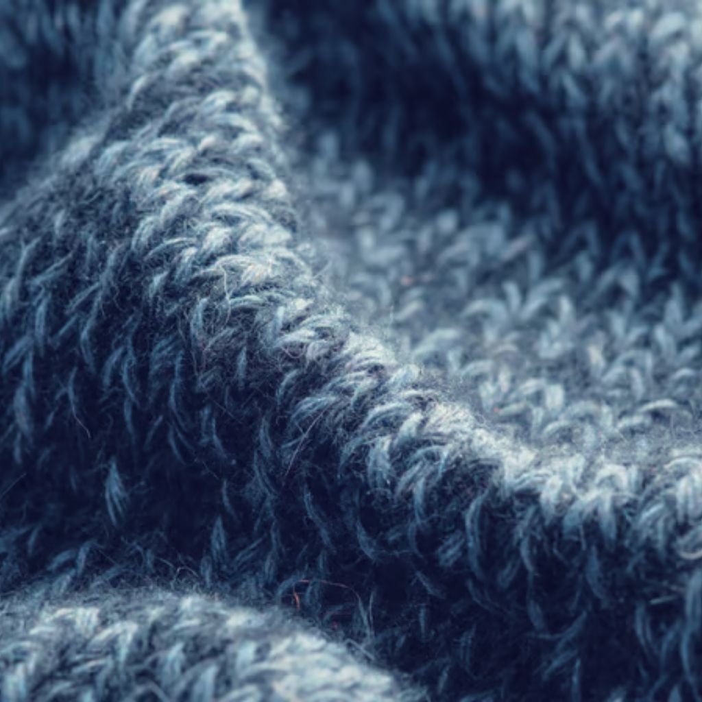 What Is Thermal Core Fabric for Winter Wear? Complete Guide 9 Alt text: Close-up of folded, dusty blue knitted fabric with a fuzzy texture, showing visible loops and strands and subtle color variations.
What Is Thermal Core Fabric for Winter Wear?