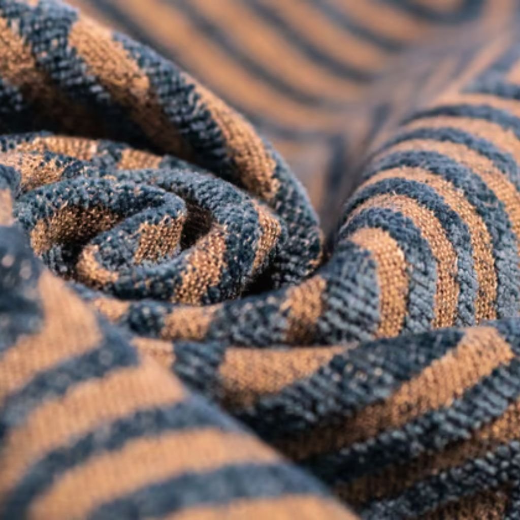 Alt text (short, screen-reader friendly): Close-up of rolled fabric with dark teal and light tan stripes arranged in a circular shape; texture of the weave is visible.
What Is Heat Wave Wool Blend?
