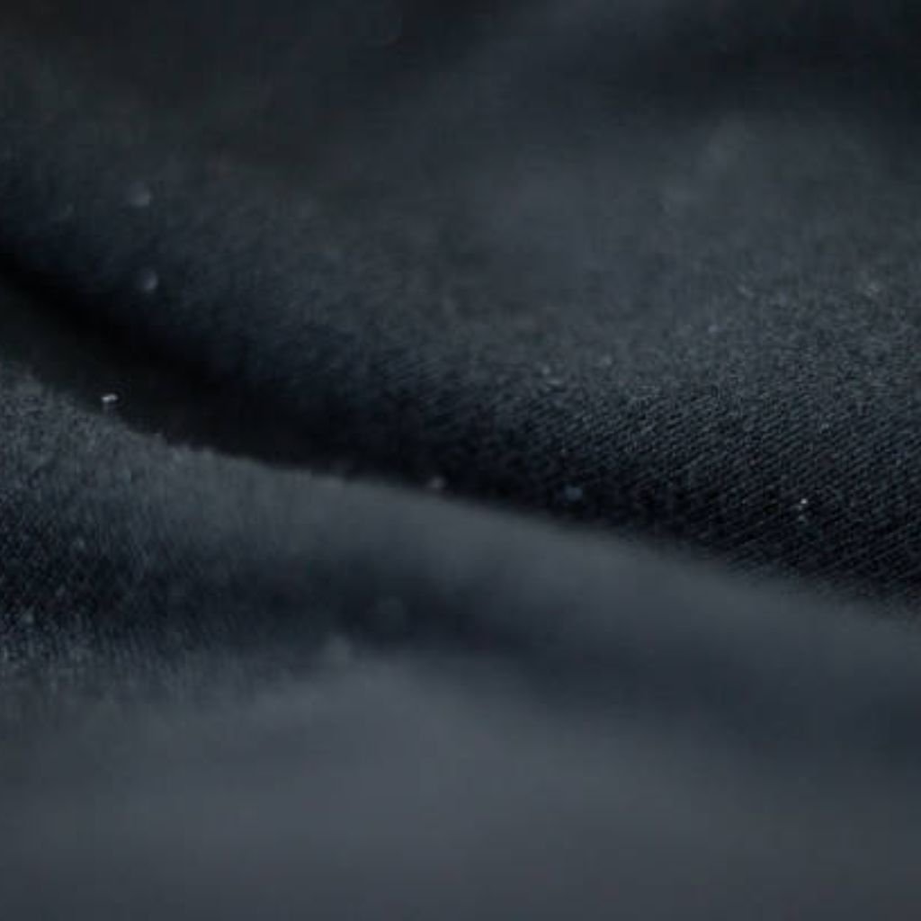 Close-up of dark blue fabric with a subtle diagonal weave, soft texture, and a few white specks on the surface.What Is Cryo Comfort Winter Fabric?
