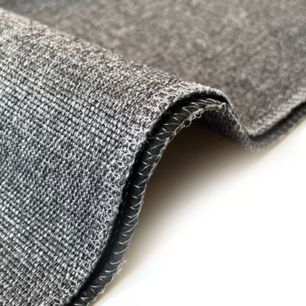 Polar Guard Heat Retention Fabric: Comfort Meets Performance 9 Alt text: Close-up of folded gray woven fabric with a visible seam and white stitching along the edge; cross-hatched texture and a white surface visible at the bottom right.
Polar Guard Heat Retention Fabric: