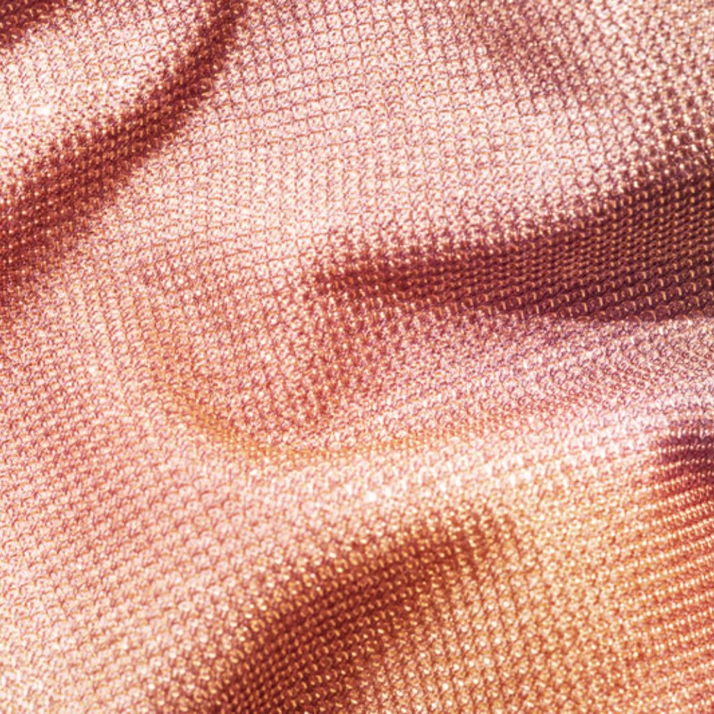Warm Aura Fabric Explained:Why It’s Perfect for Cold Weather 8 Alt text: Close-up of draped shimmering woven fabric in orange, copper, and light gold tones. The small textured pattern catches the light, with folds creating highlights and shadows.
Warm Aura Fabric Explained:
