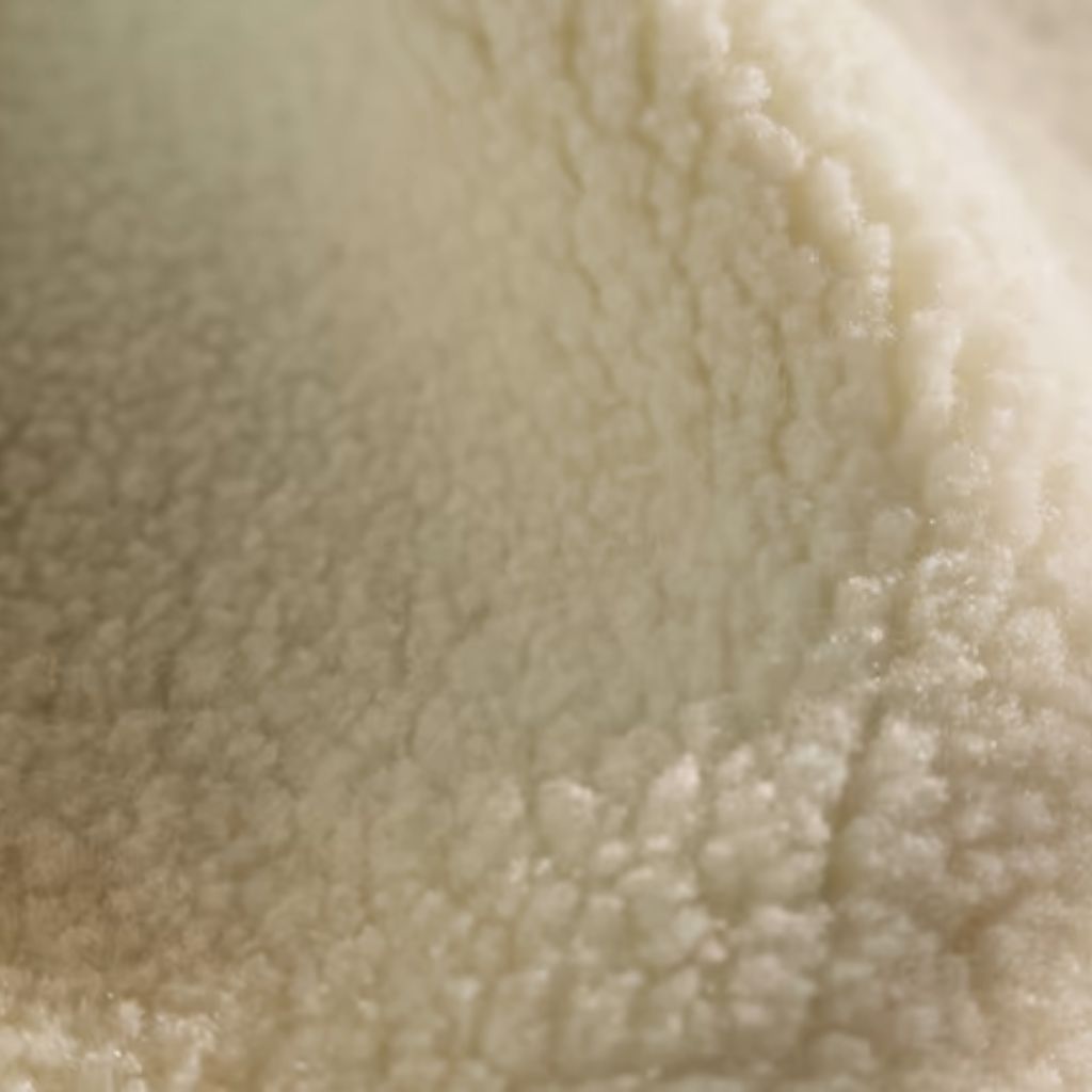 Alt text: Close-up of white fluffy fabric, likely fleece or wool, with a soft, uneven texture and subtle light-shadow variations throughout.
Polar Prime Fabric Guide:
