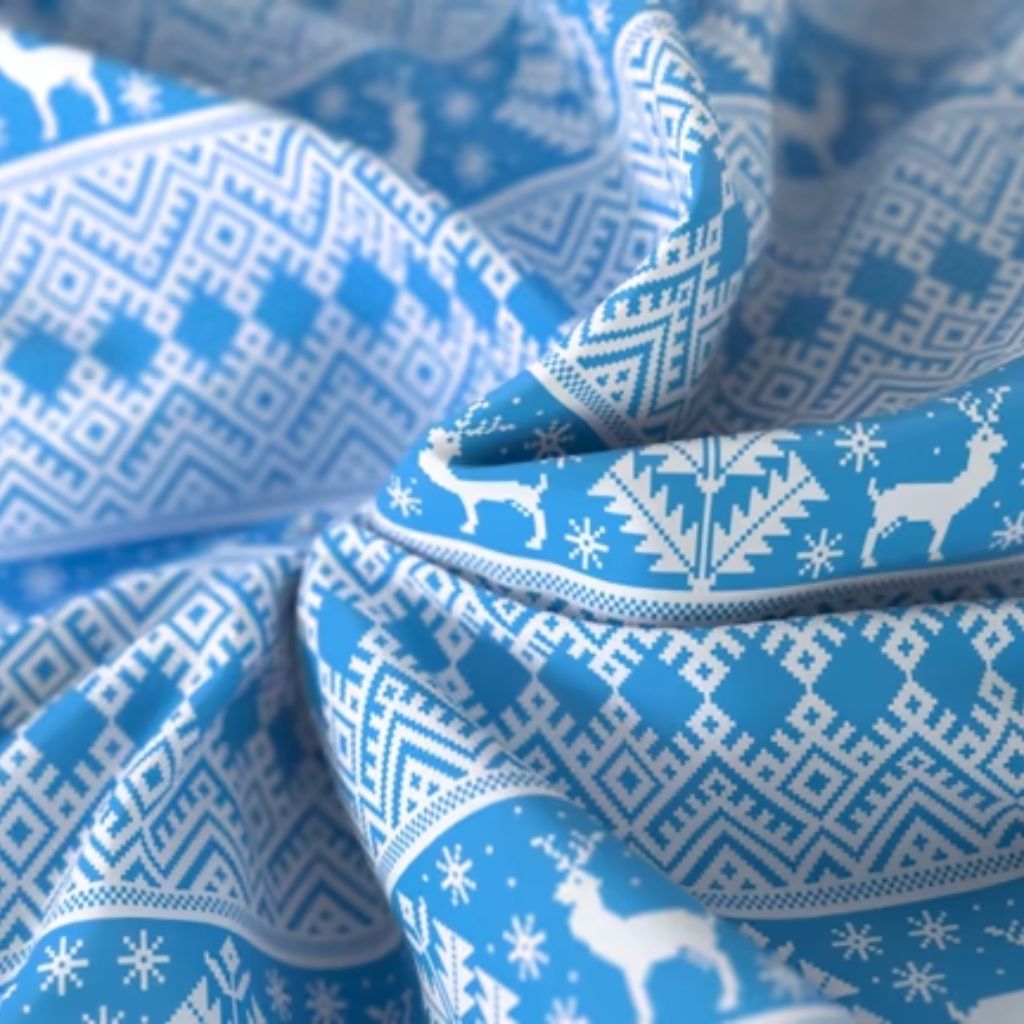 Winter Crown Insul-Fabric Guide: Benefits, Features & Uses 9 Close-up of blue and white fabric with a Nordic-inspired pattern featuring geometric shapes, snowflakes, and reindeer, arranged in folds and curves.Winter Crown Insul-Fabric Guide: