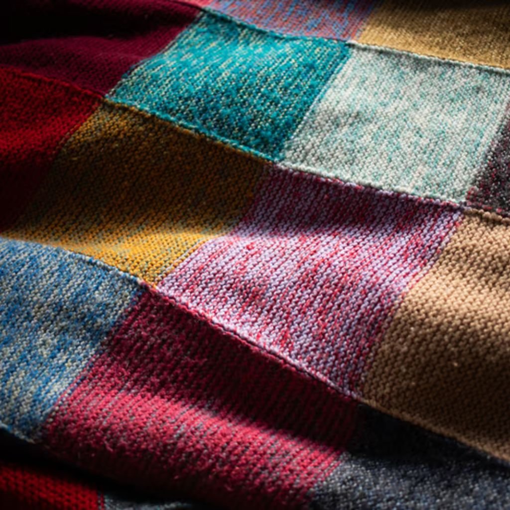 Sustainable Wool Fabric: Natural Warmth with a Green Promise 9 Alt text: Close-up of colorful woven fabric with a patchwork pattern, showing various plaid and striped sections in red, blue, green, yellow, and brown.
Sustainable Wool Fabric: