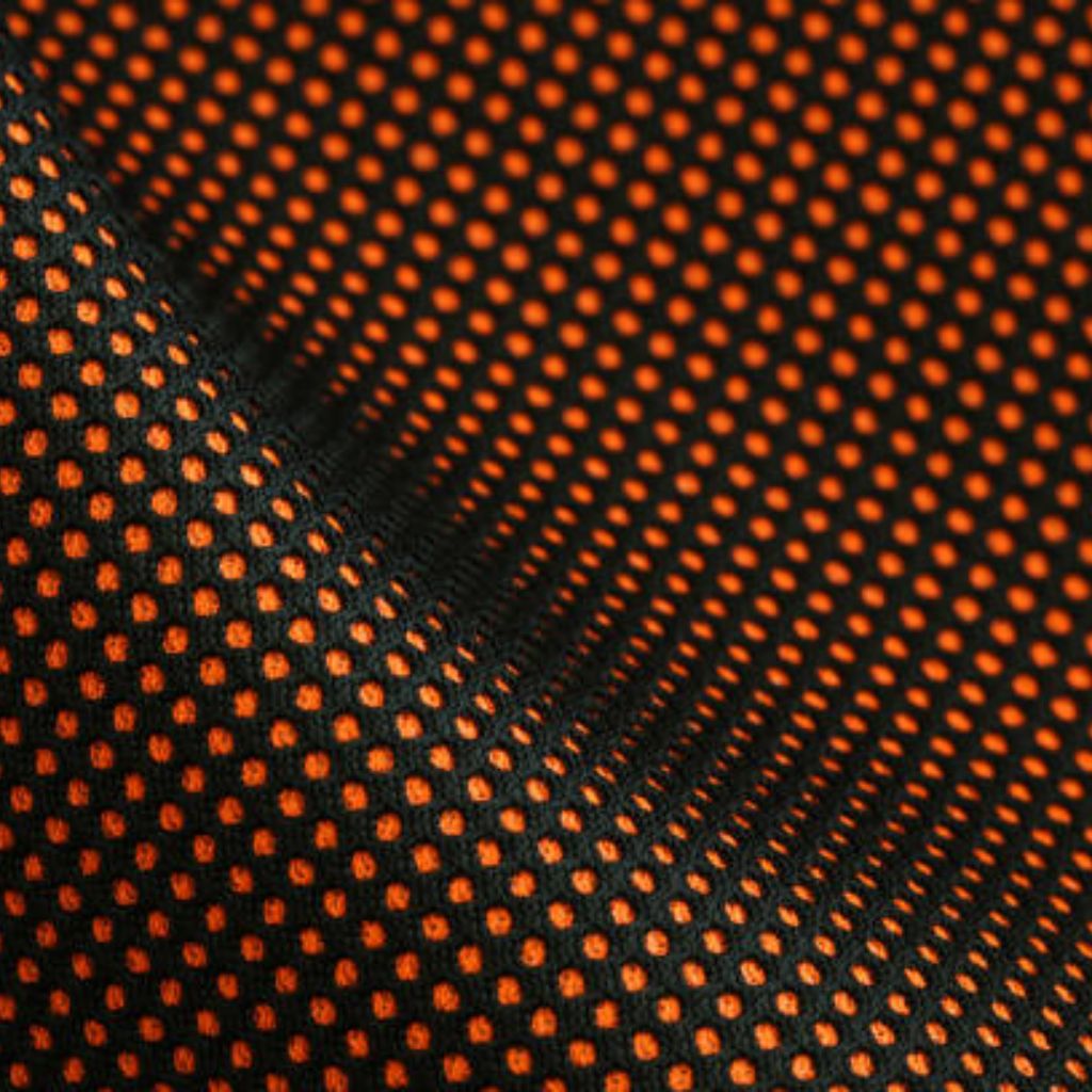 Close-up of black fabric with small orange polka dots, showing a diagonal crease that adds depth to the textured surface.
Heat Core Insulated Sports Textile: