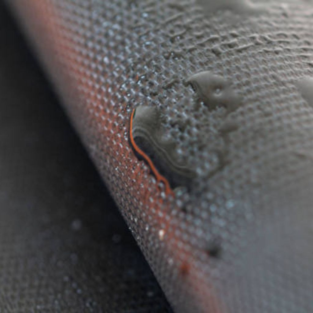 Thermo Shield Performance Fabric: Technology for Activewear 9 Macro shot of water droplets on a dark gray textured surface with a subtle orange stripe.
Thermo Shield Performance Fabric: