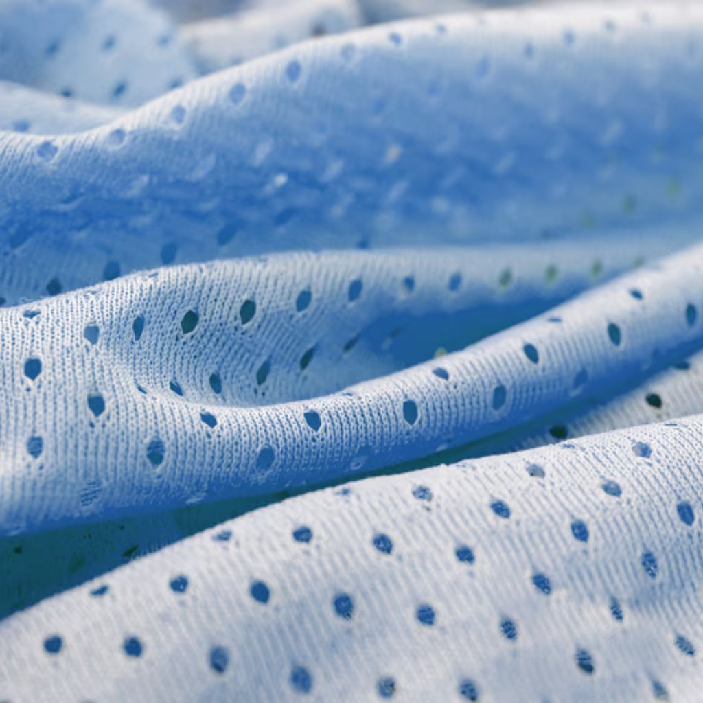 Close-up of blue and white mesh-like fabric with evenly spaced holes, draped in soft folds.
Aqua Dry Cooling Active Fabric: