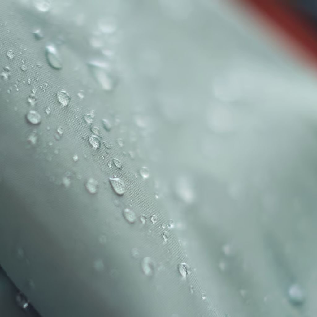 Alt text: "Close-up macro of light gray fabric with scattered water droplets."
Does Storm-Proof Fabric: