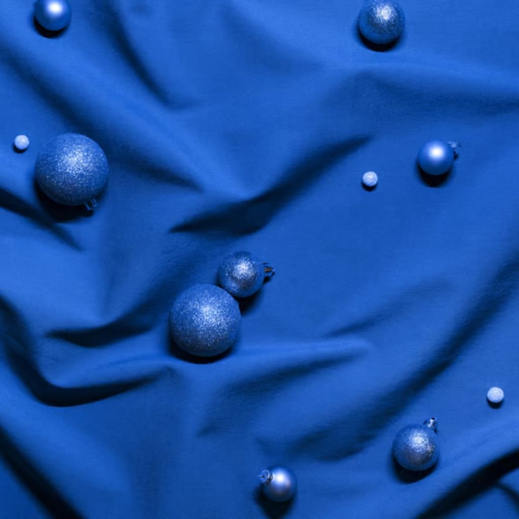 A royal blue fabric is spread out with glittery blue Christmas ornaments of varying sizes placed on it. The fabric shows creases and shadows, while the ornaments add texture and sparkle.
How Gore-Tex Fabric Works:
