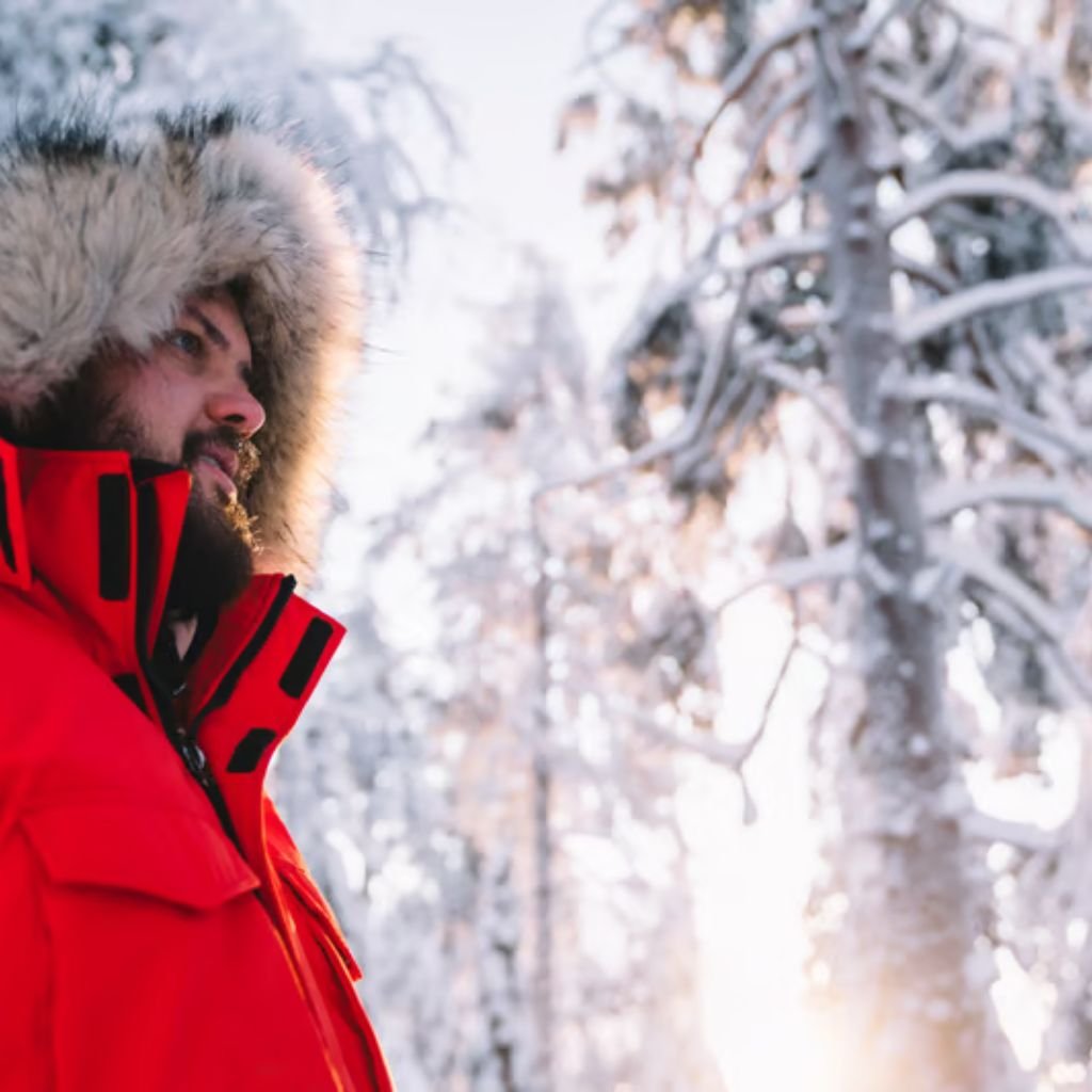 "Close-up of a bearded man in a red parka with a fur-lined hood standing in a snowy forest with sunlit snow on the trees."

Ultra-Warm Thermal Winter Coat: