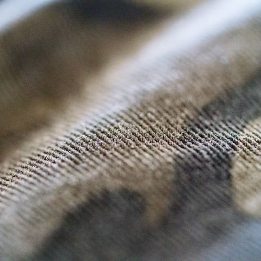 Alt text: Close-up view of textured camouflage fabric with intersecting fibers in brown, gray, and white tones.
Wind Armor Fabric: