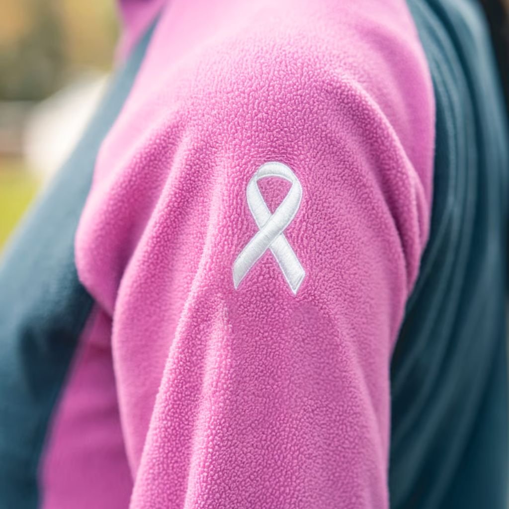 Alt text: Close-up of a pink fleece jacket sleeve with a white ribbon-style breast cancer awareness emblem.
What Is Wind Armor Extreme Fabric?