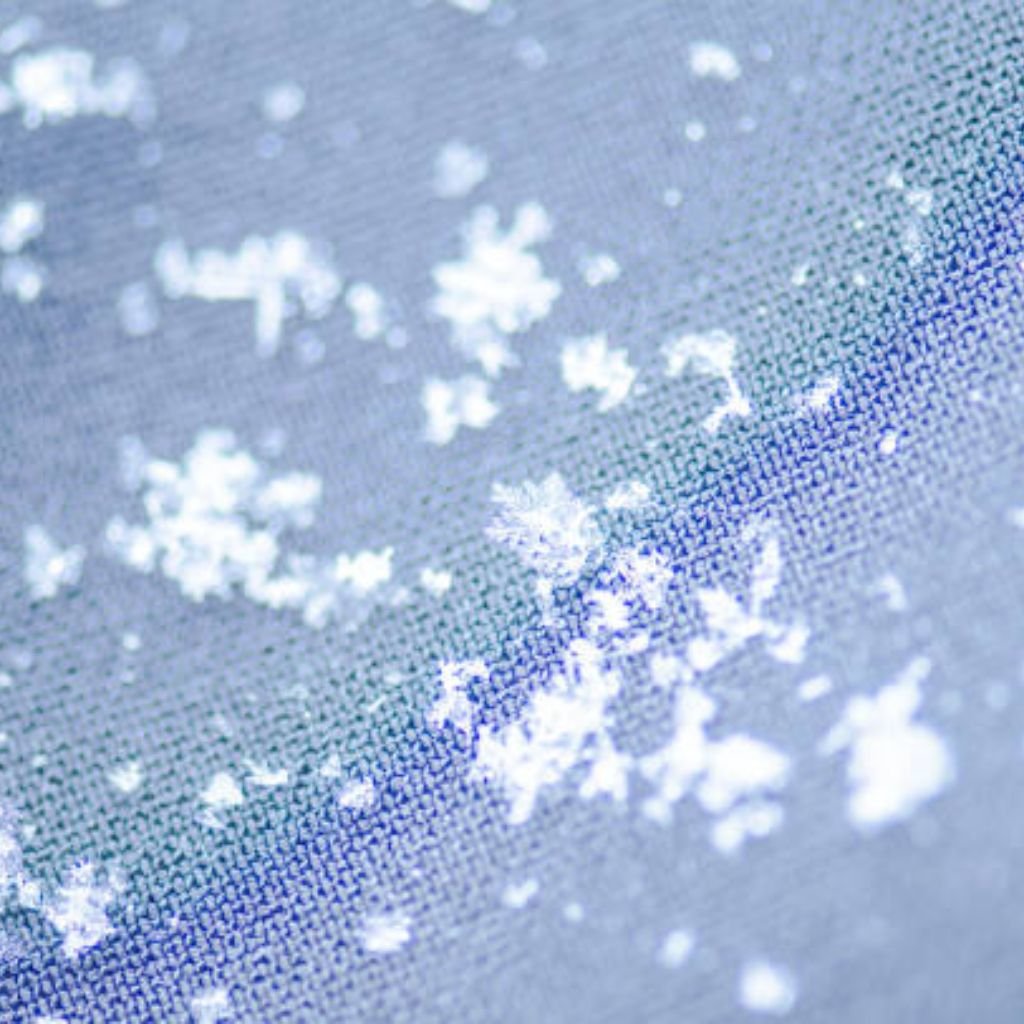 What Is Winter Lock Performance Fabric? Features & Benefits 10 Alt text: Close-up of white snowflakes resting on a blue and grey woven fabric, with visible texture.
What Is Winter Lock Performance Fabric?