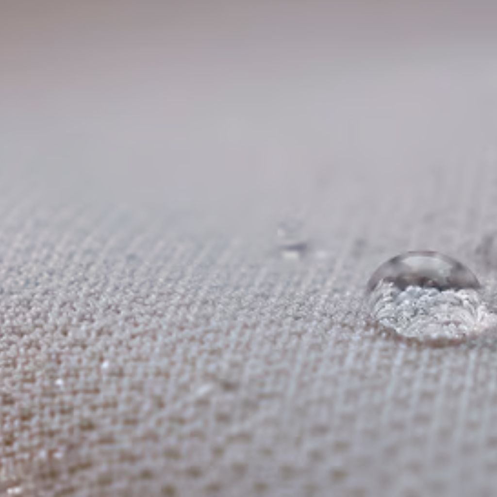 Polar Guard Heat Retention Fabric: Comfort Meets Performance 10 Alt text: Close-up of a large water droplet resting on a light-colored woven textile, with a smaller droplet in the background; the fabric texture is clearly visible.
Polar Guard Heat Retention Fabric: