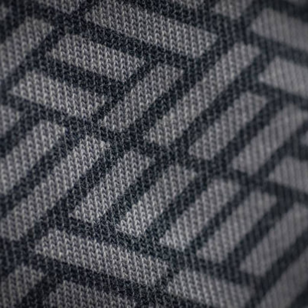 WarmTech Elite Athletic Weave: Next-Gen Athletic Fabric Tech 11 Alt text: Close-up of gray knitted fabric with a dark geometric grid pattern formed by interlocking stitches.WarmTech Elite Athletic Weave: