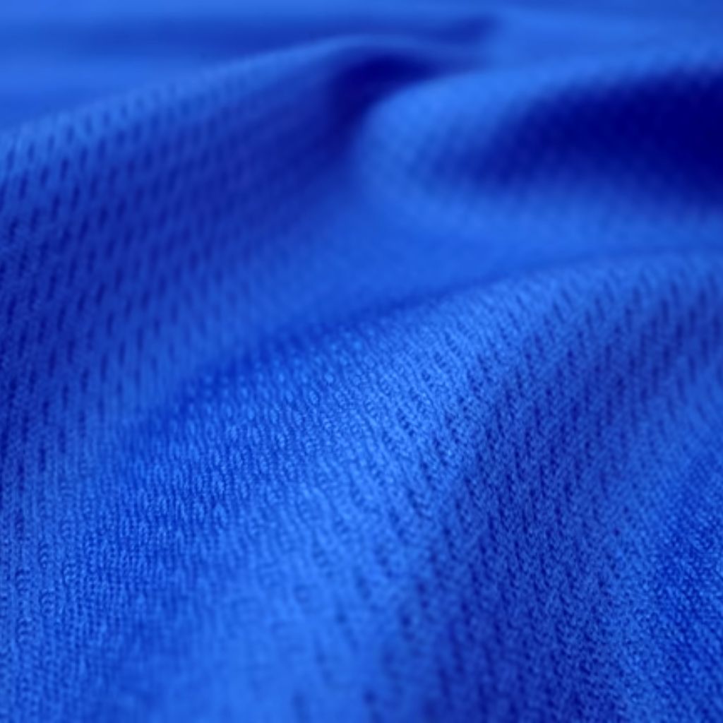 Close-up of vibrant blue fabric with a subtle mesh-like texture and tiny hole pattern, draped to form soft folds and curves.
Heat Core Insulated Sports Textile: