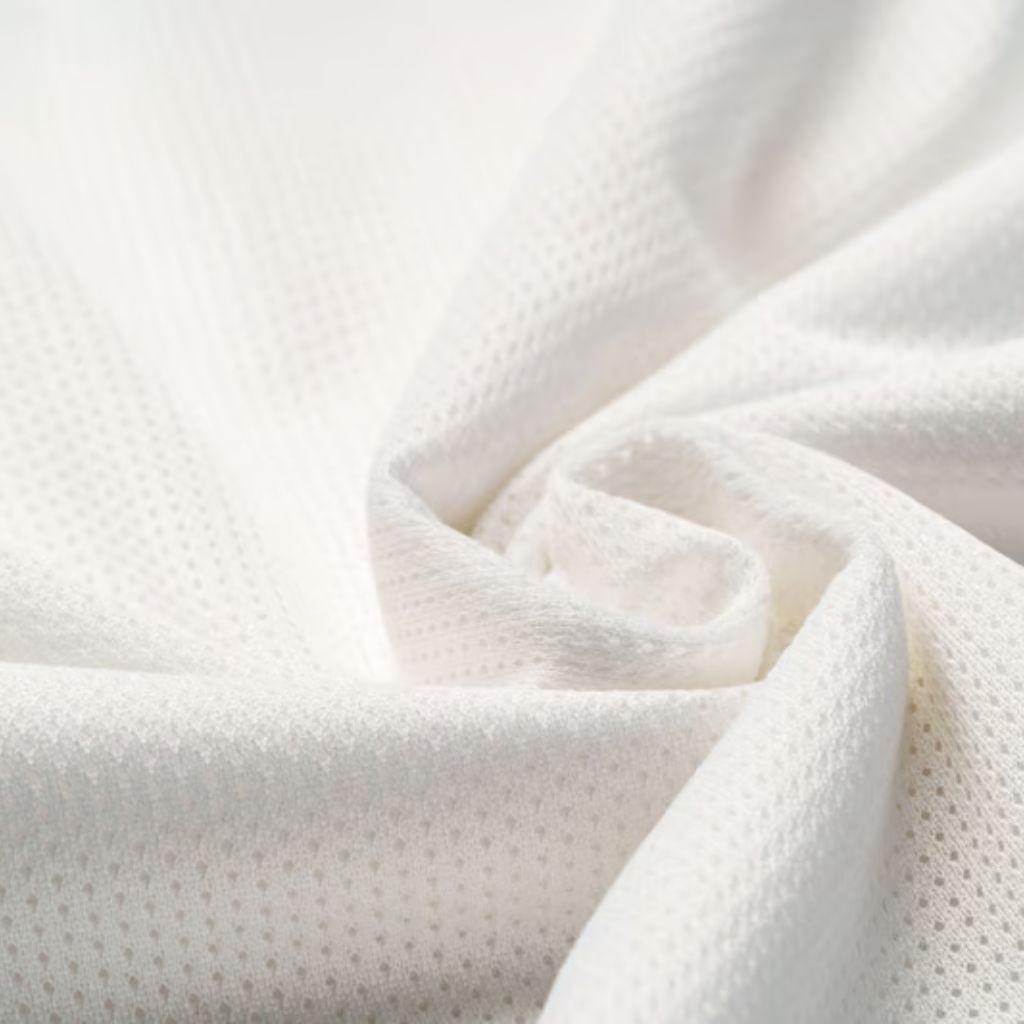 Close-up of white, porous fabric with a net-like texture, softly folded to create gentle curves and shadows.
Aqua Dry Cooling Active Fabric: