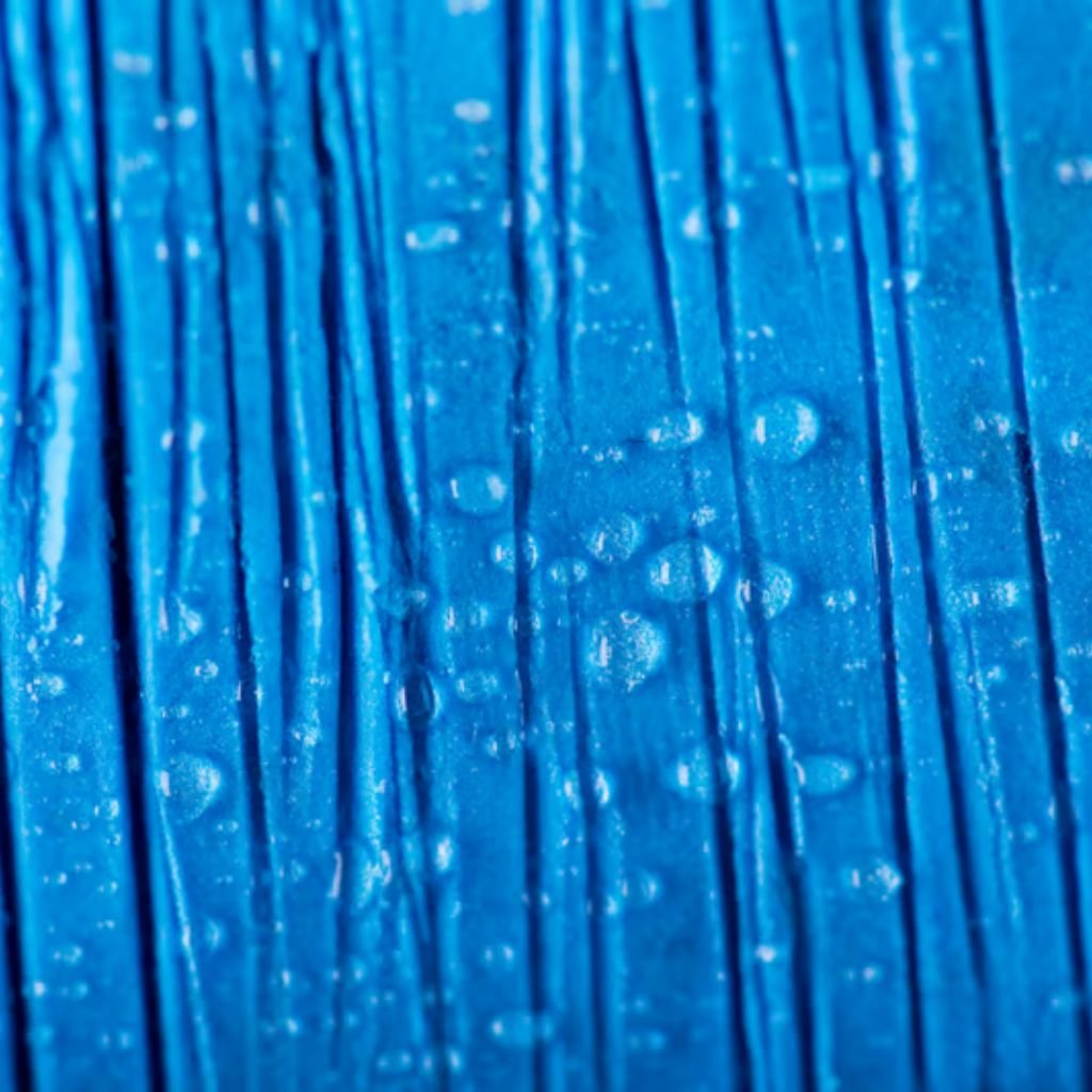 Alt text: "Macro close-up of blue textured fabric with vertical ridges and scattered water droplets."Does Storm-Proof Fabric:
