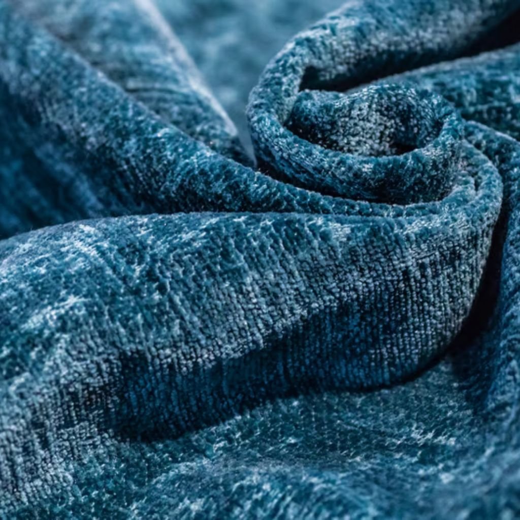 "Close-up of plush blue velvet fabric with soft folds and a textured surface, suggesting rich, warm material suitable for winter jackets."
Velvet Warm Fabric Explained:
